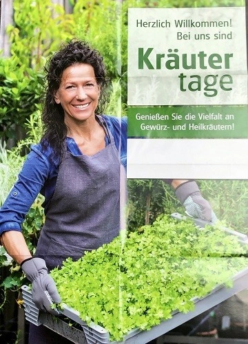 Blumen Pechloff – Mitarbeiterin hält charmant lächelnd einen handgemachten Blumenstrauß mit Herz in die Kamera